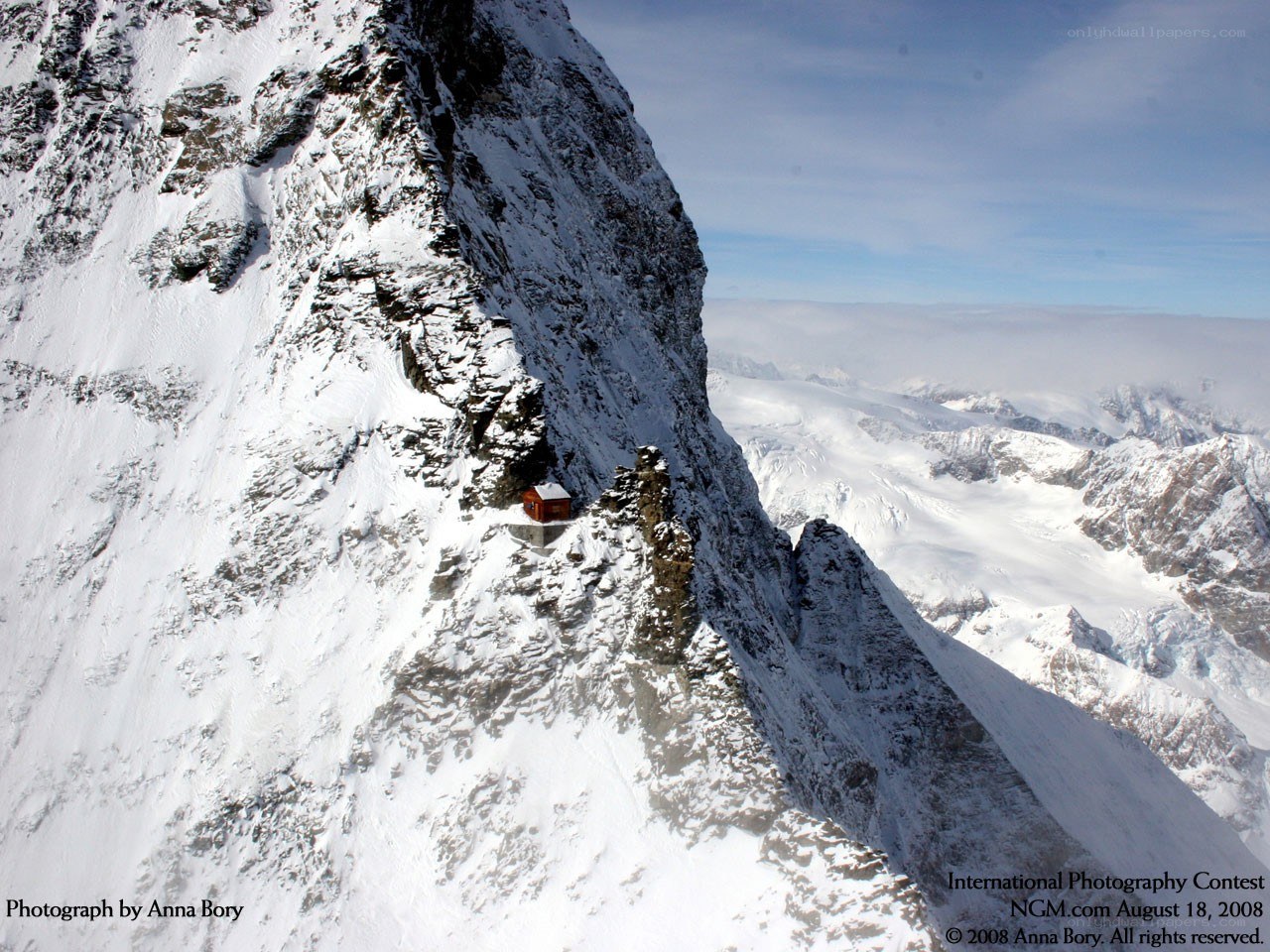 Mountain hut on snowy cliff