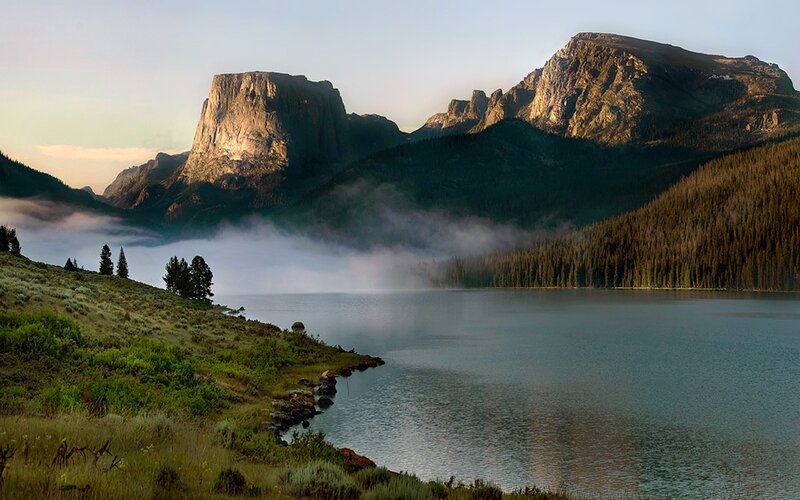 Mountain lake at sunrise with fog