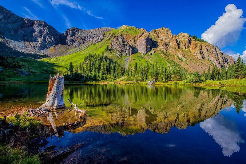 Mountain Lake Reflection — Blue, Serene, Afternoon, Photograph, Mountains, Trees, Driftwood