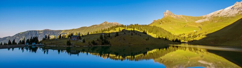 Mountain Lake Reflection — Blue, Serene, Morning, Photograph, Mountains, Trees, Building, Green, Brown
