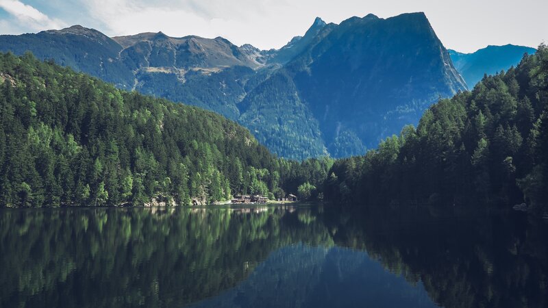 Mountain Lake Reflection — Green, Serene, Afternoon, Photograph, Mountains, Forest, Buildings