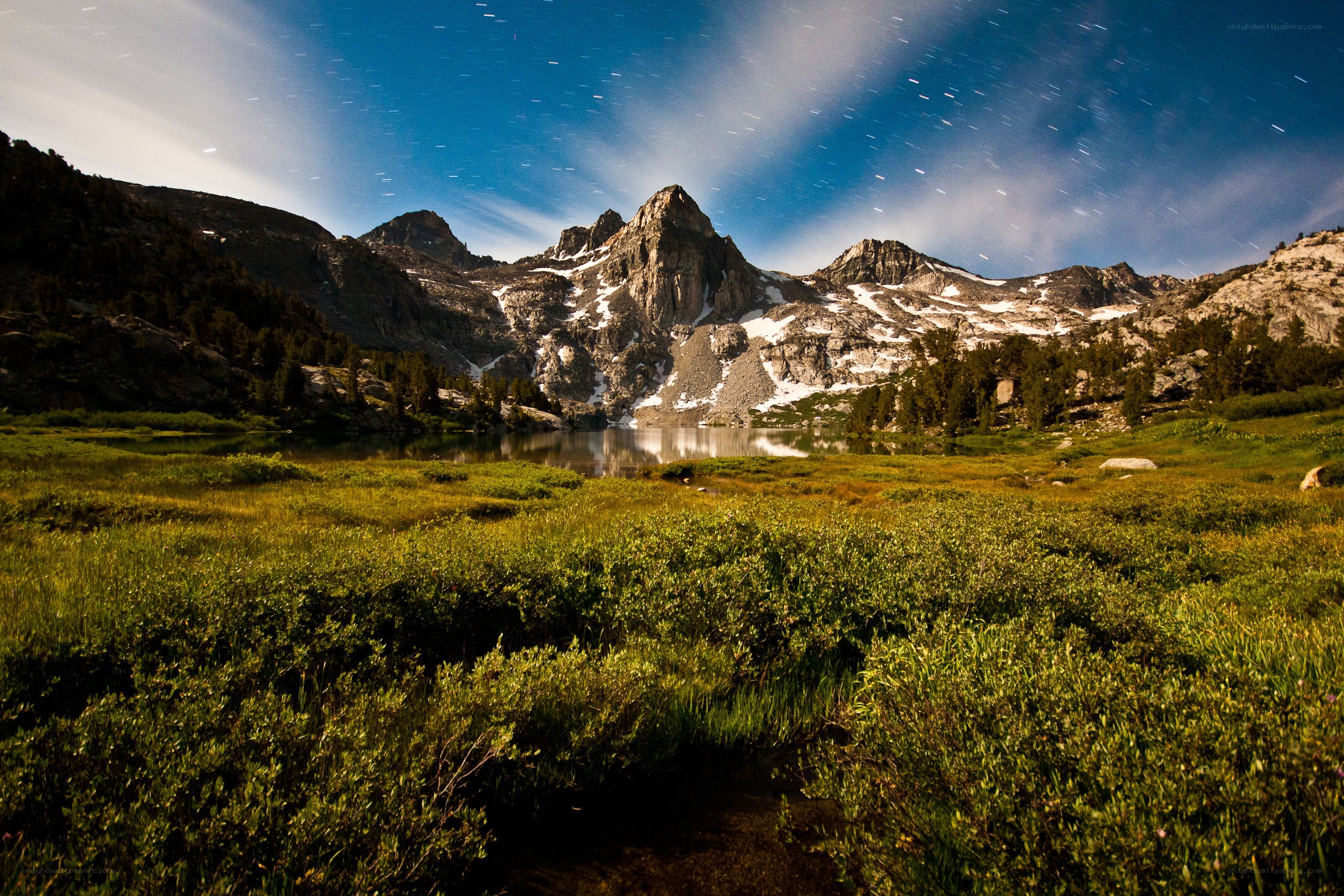 Mountain lake under star trails