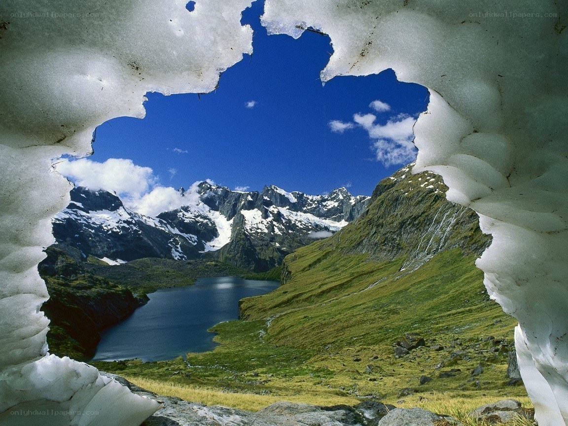 Mountain lake viewed through snow tunnel