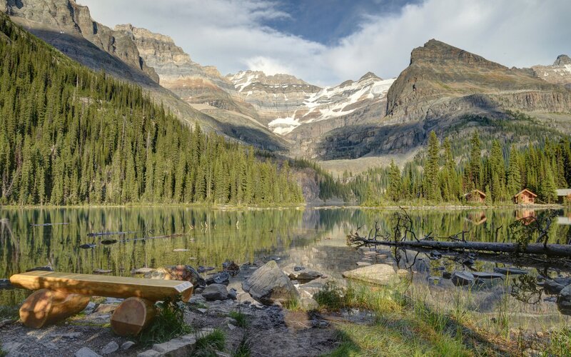 Mountain lake with cabin and bench