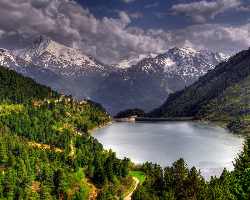 Mountain lake with dam and snow-capped peaks
