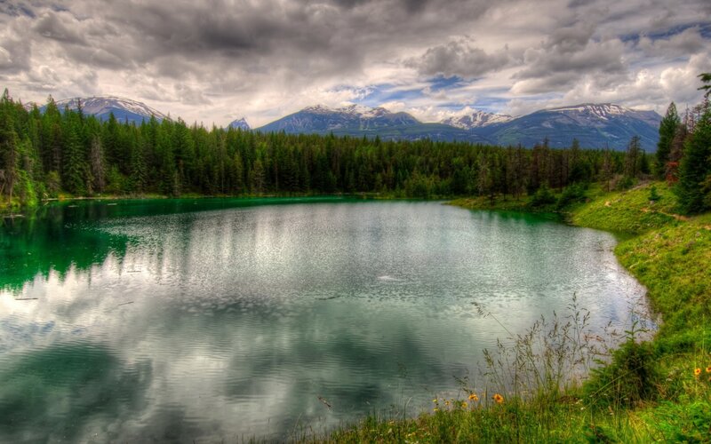 Mountain lake with forest and snow-capped peaks