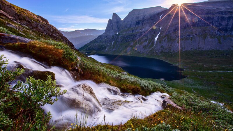 Mountain lake with waterfall at sunrise
