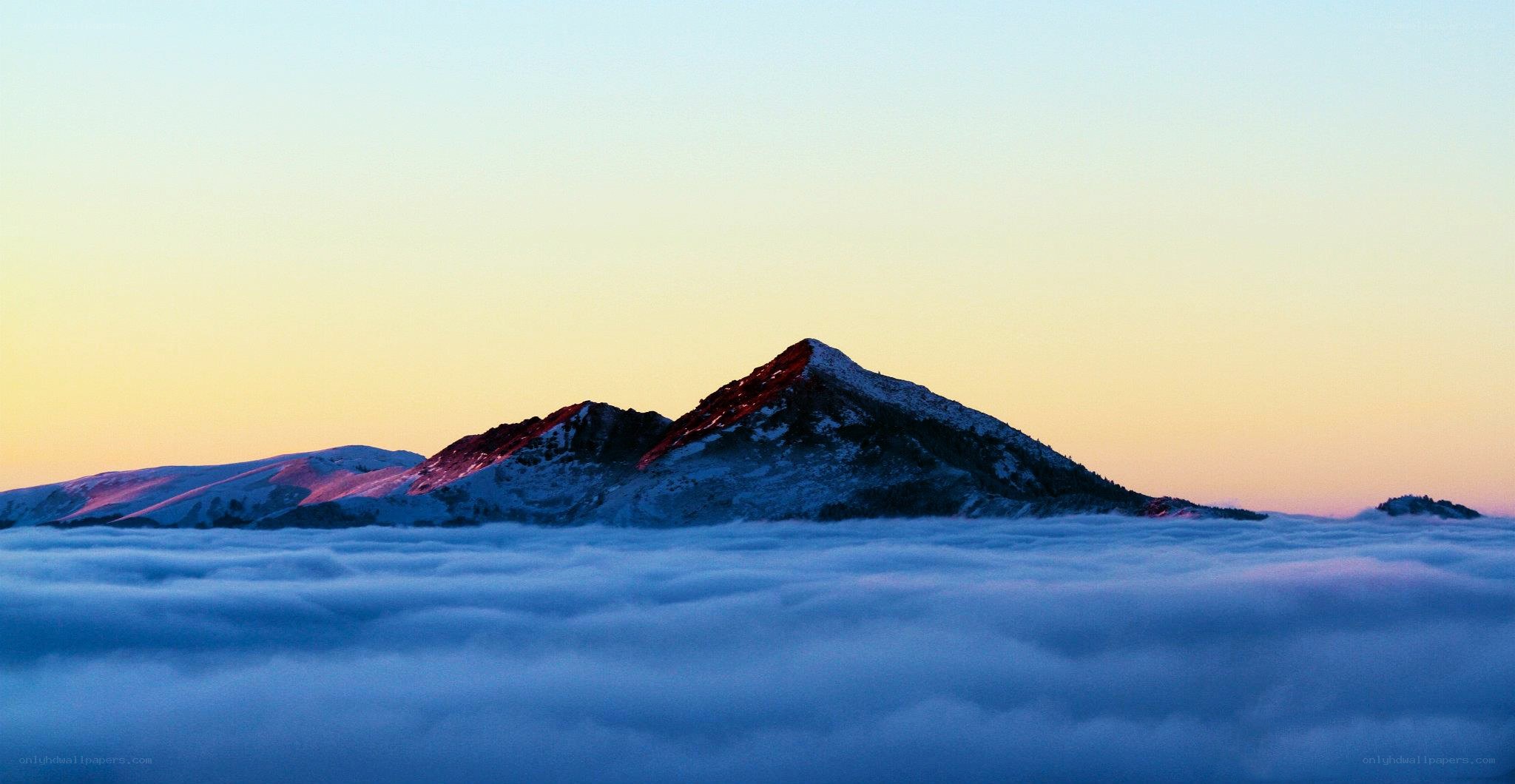 Mountain peak above clouds at sunrise