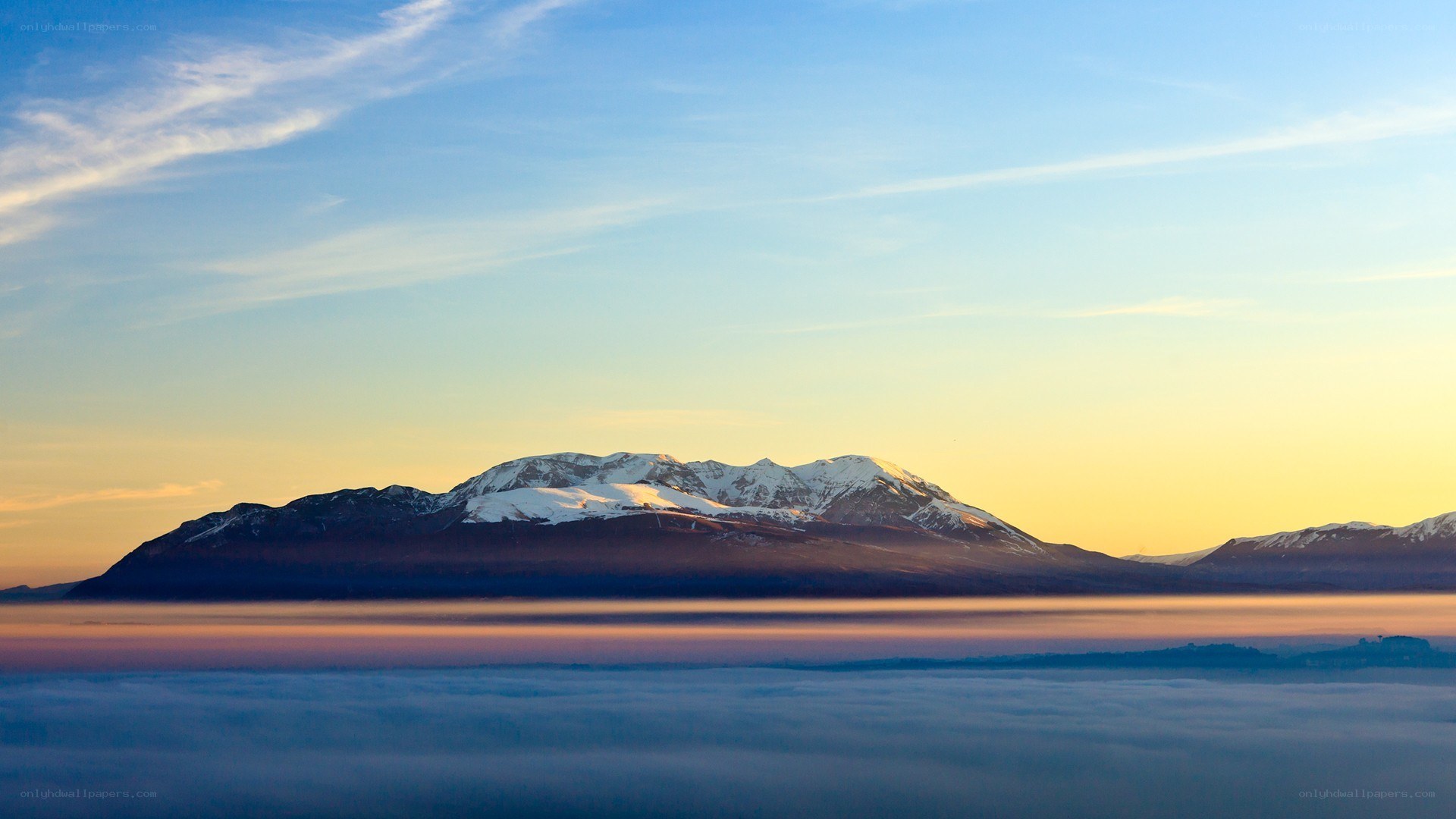 Mountain peak above clouds at sunrise