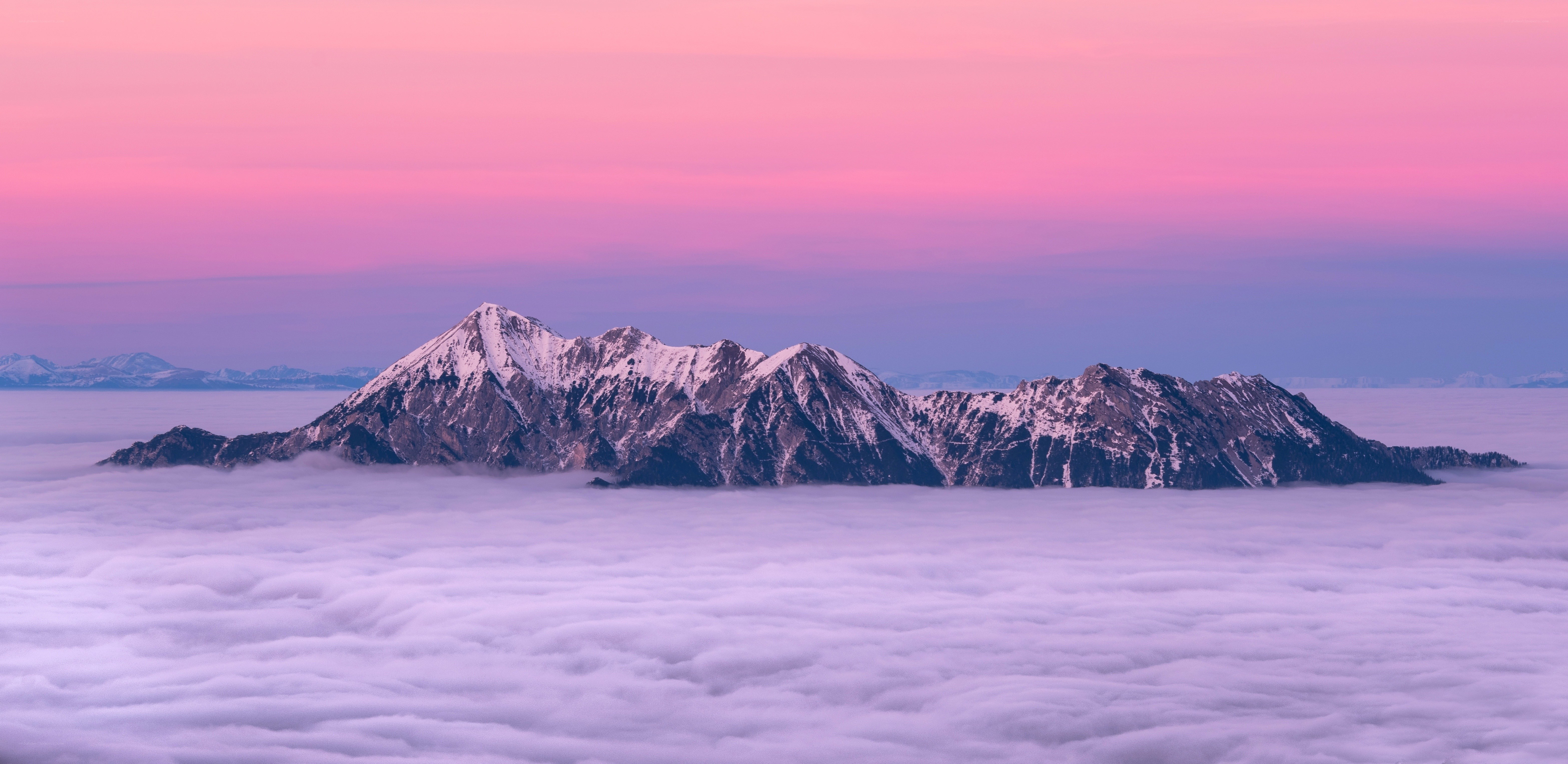 Mountain peak above clouds at sunset