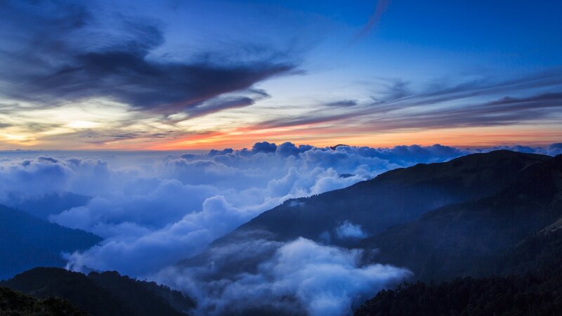 Mountain peak above clouds at sunset