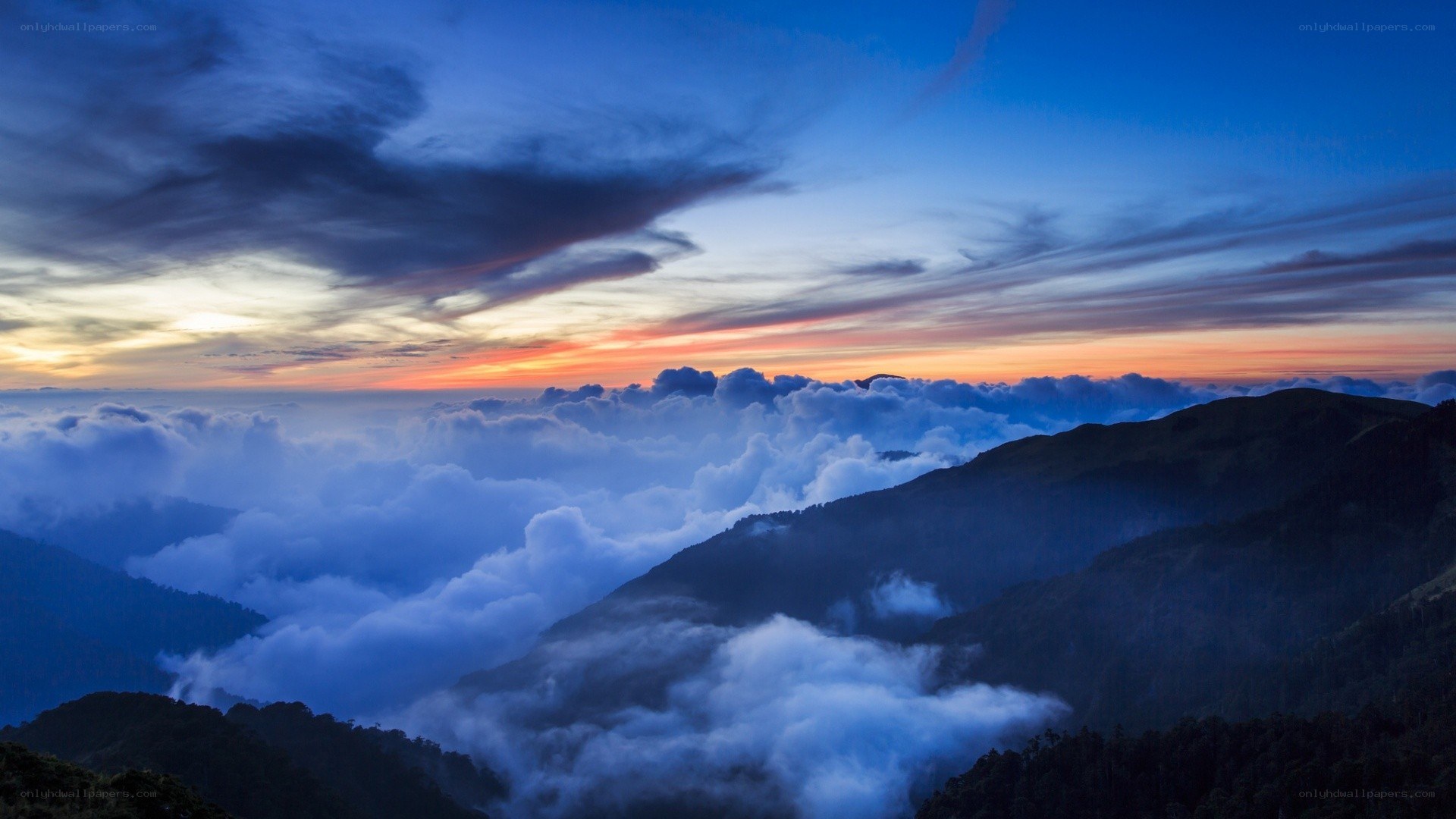Mountain peak above clouds at sunset