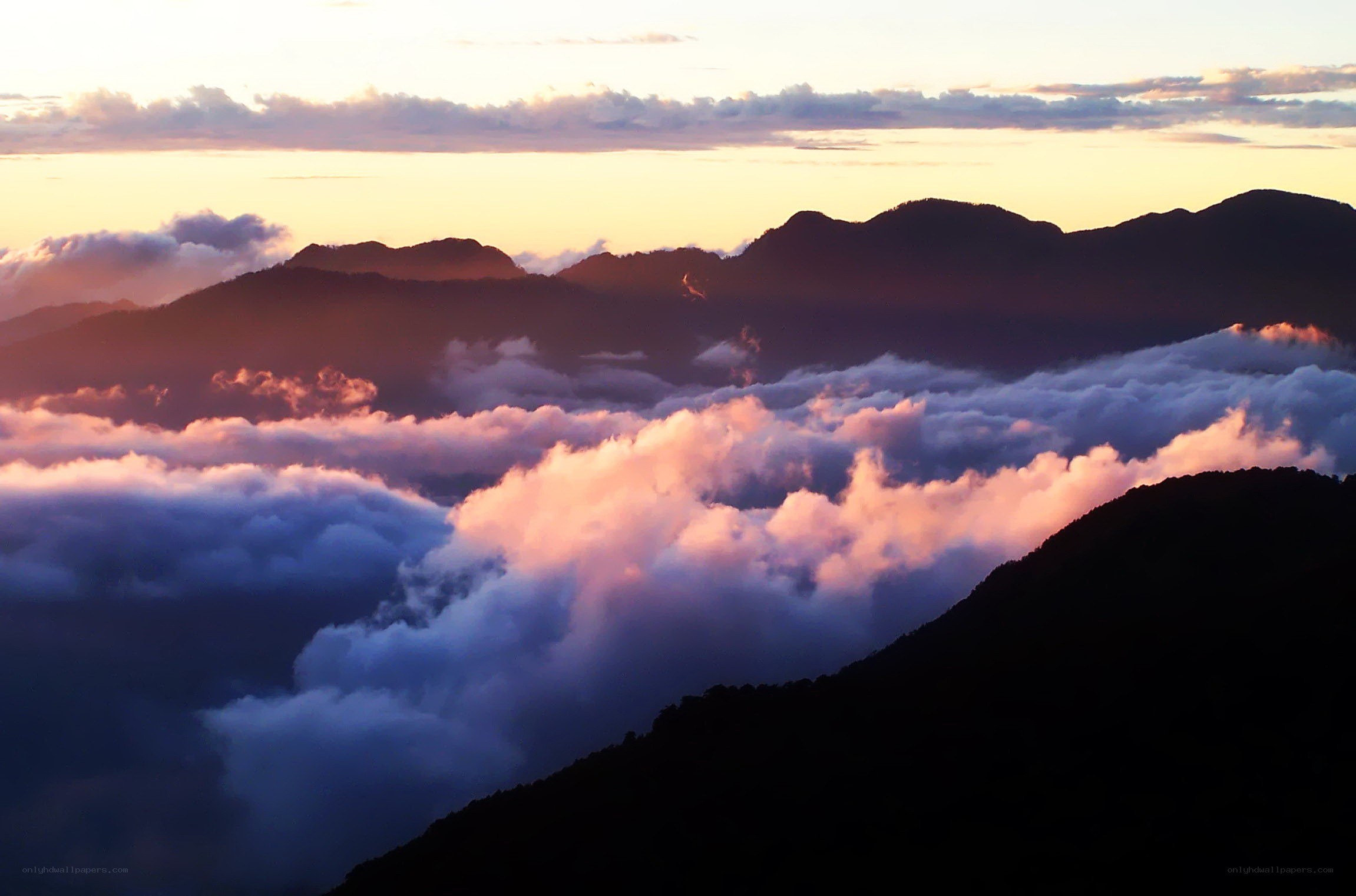 mountain peaks above clouds at sunrise