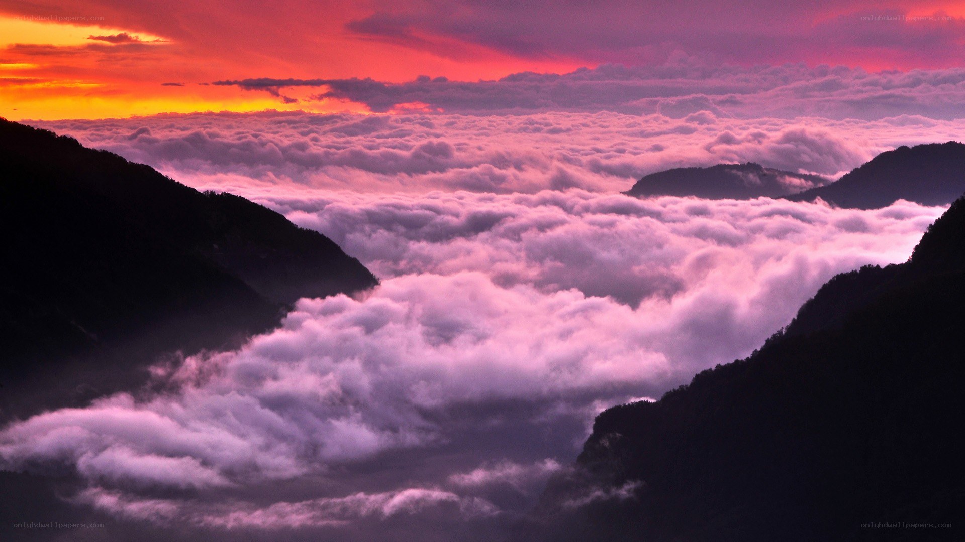 mountain peaks above clouds at sunset