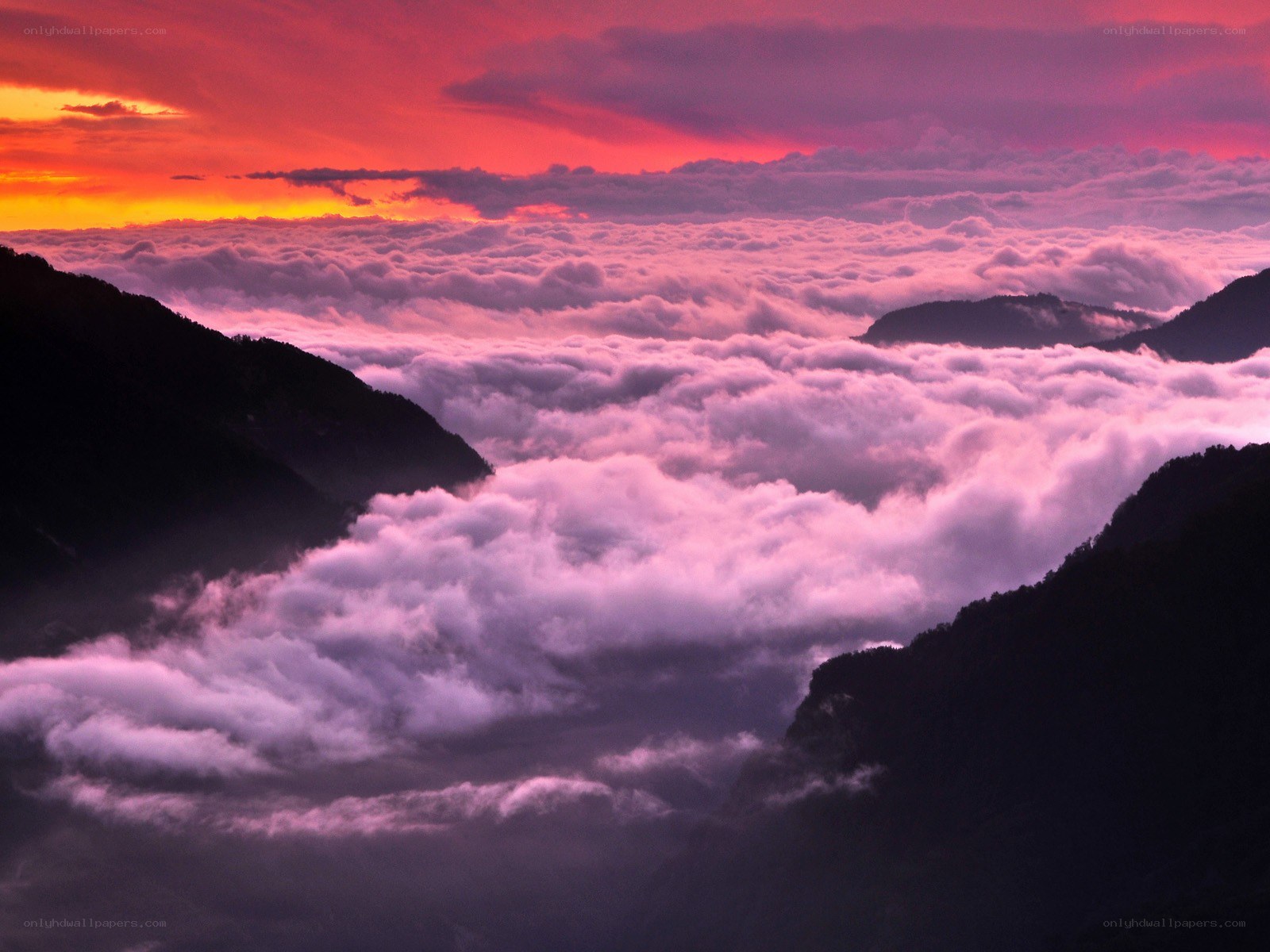 Mountain peaks above clouds at sunset