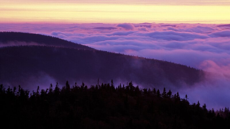 mountain peaks above clouds at sunset