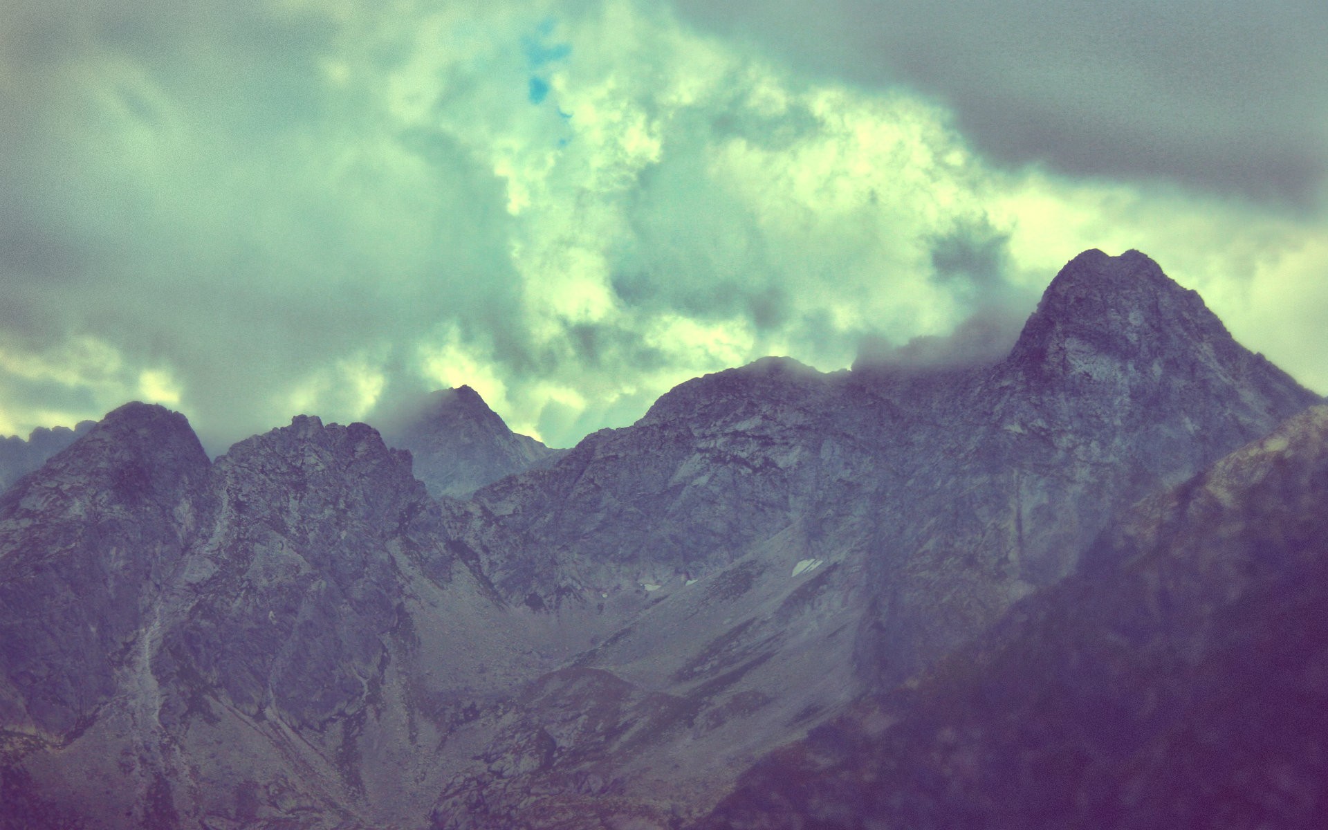 mountain peaks under cloudy sky