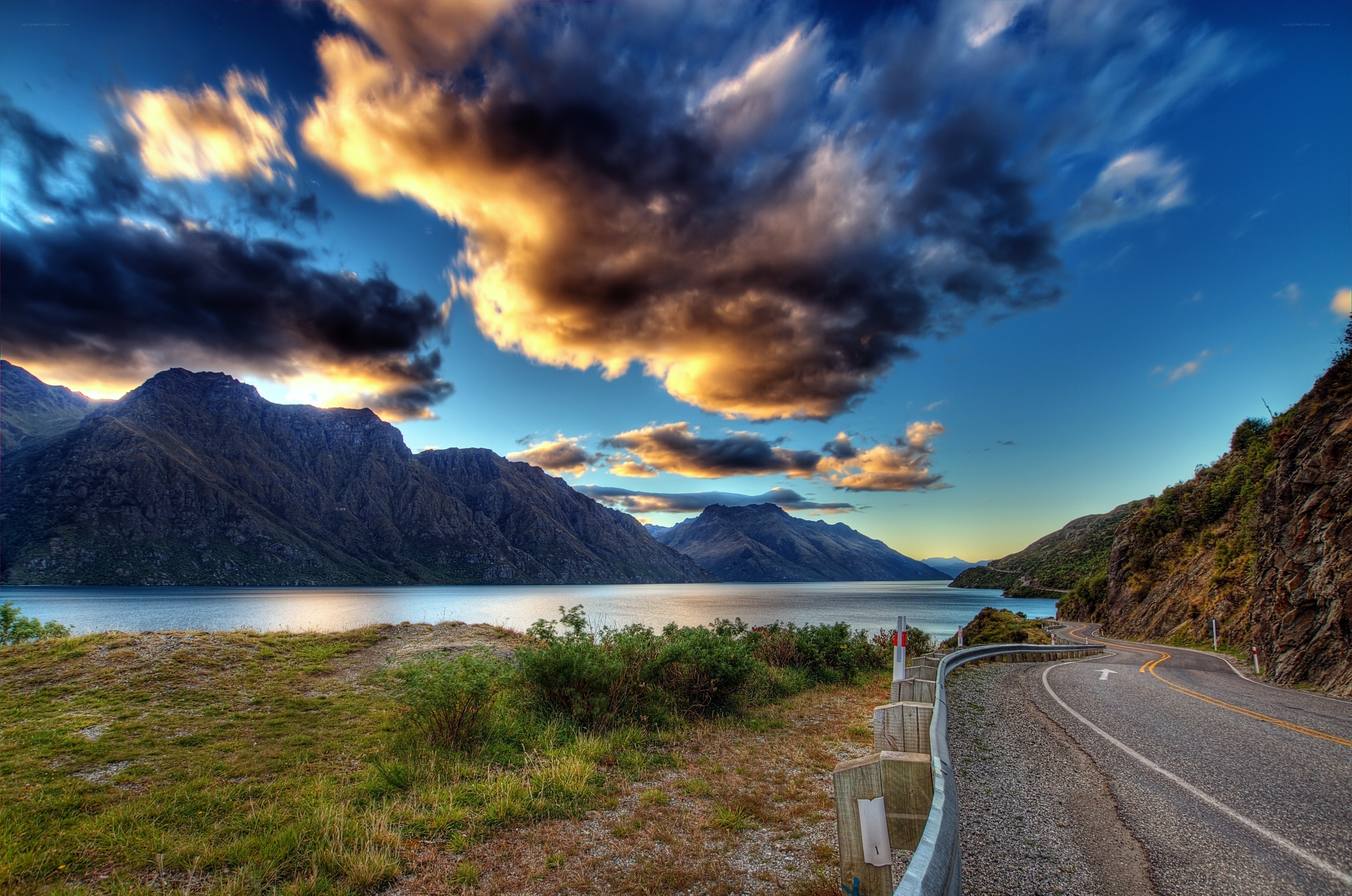 Mountain road by a lake at sunset