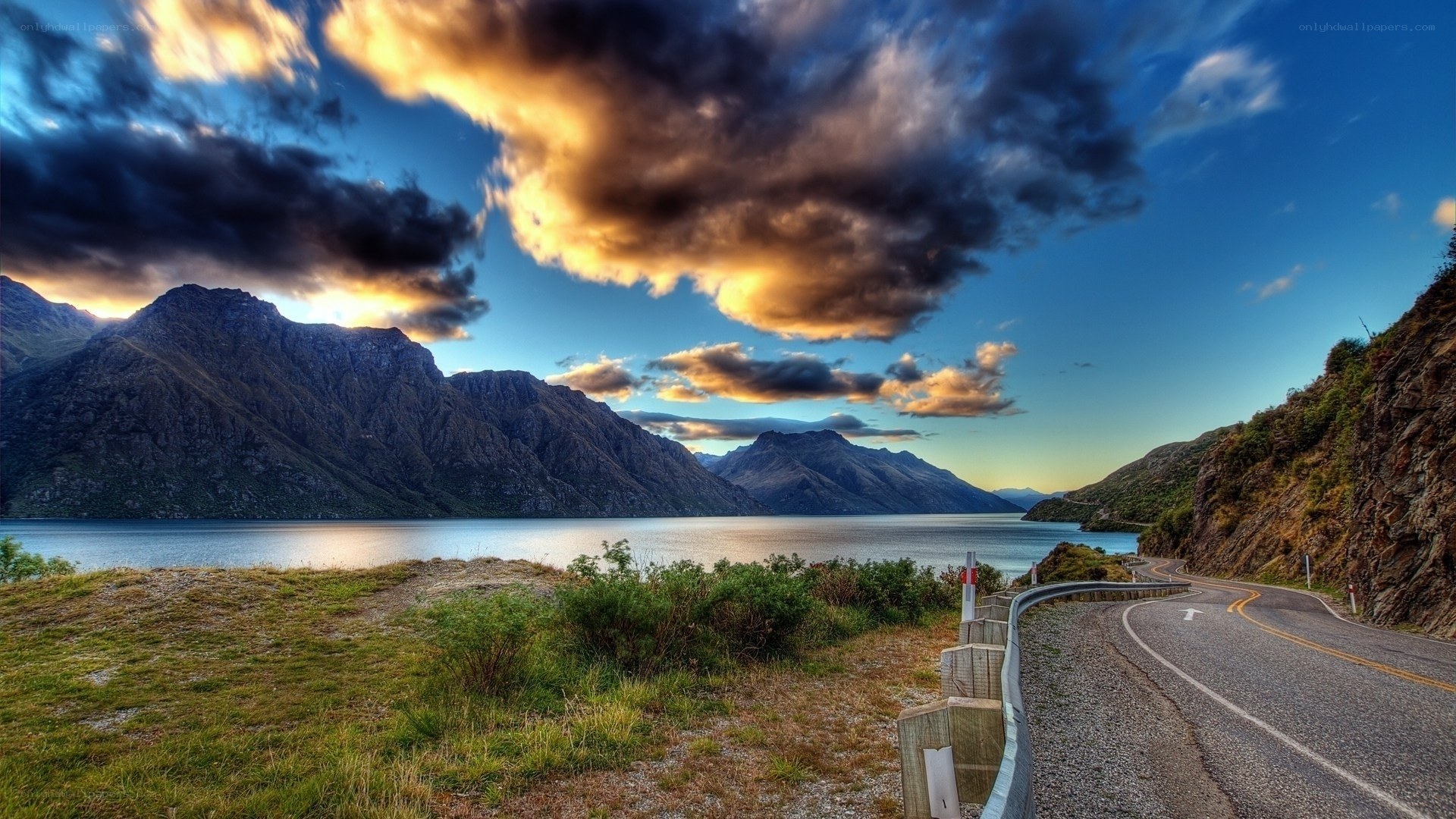 Mountain road by a lake at sunset