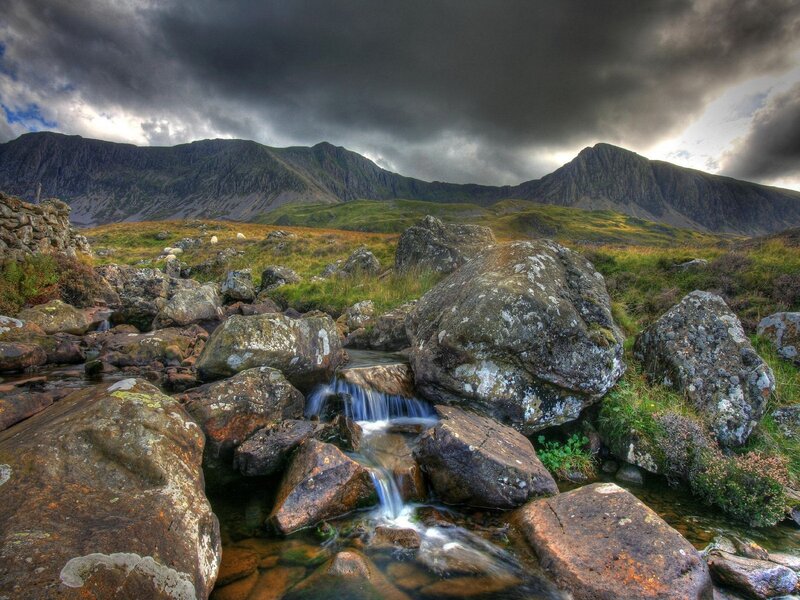 Mountain stream under stormy sky