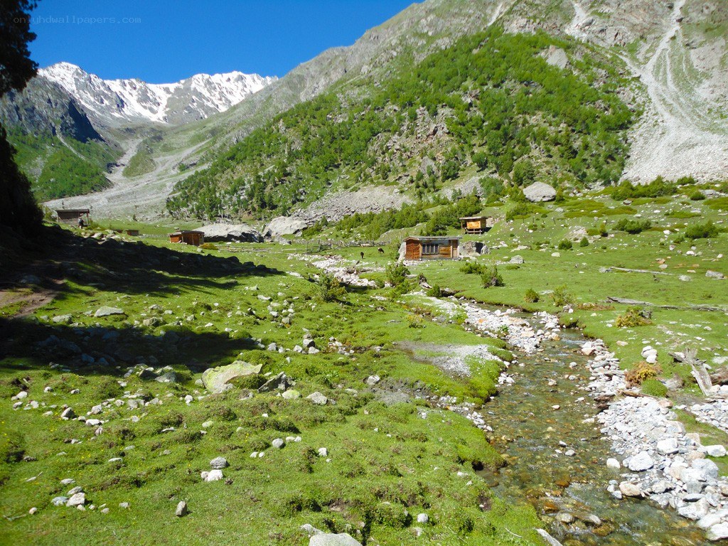 Mountain valley with stream and huts