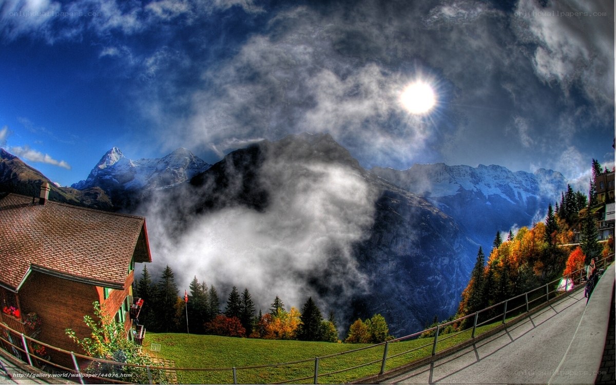 Mountain village with sun and clouds