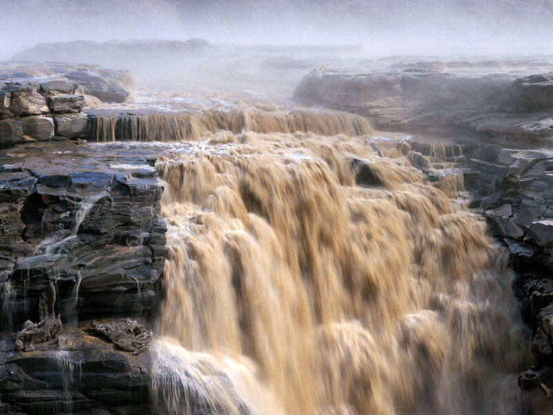 Muddy waterfall cascading over rocks