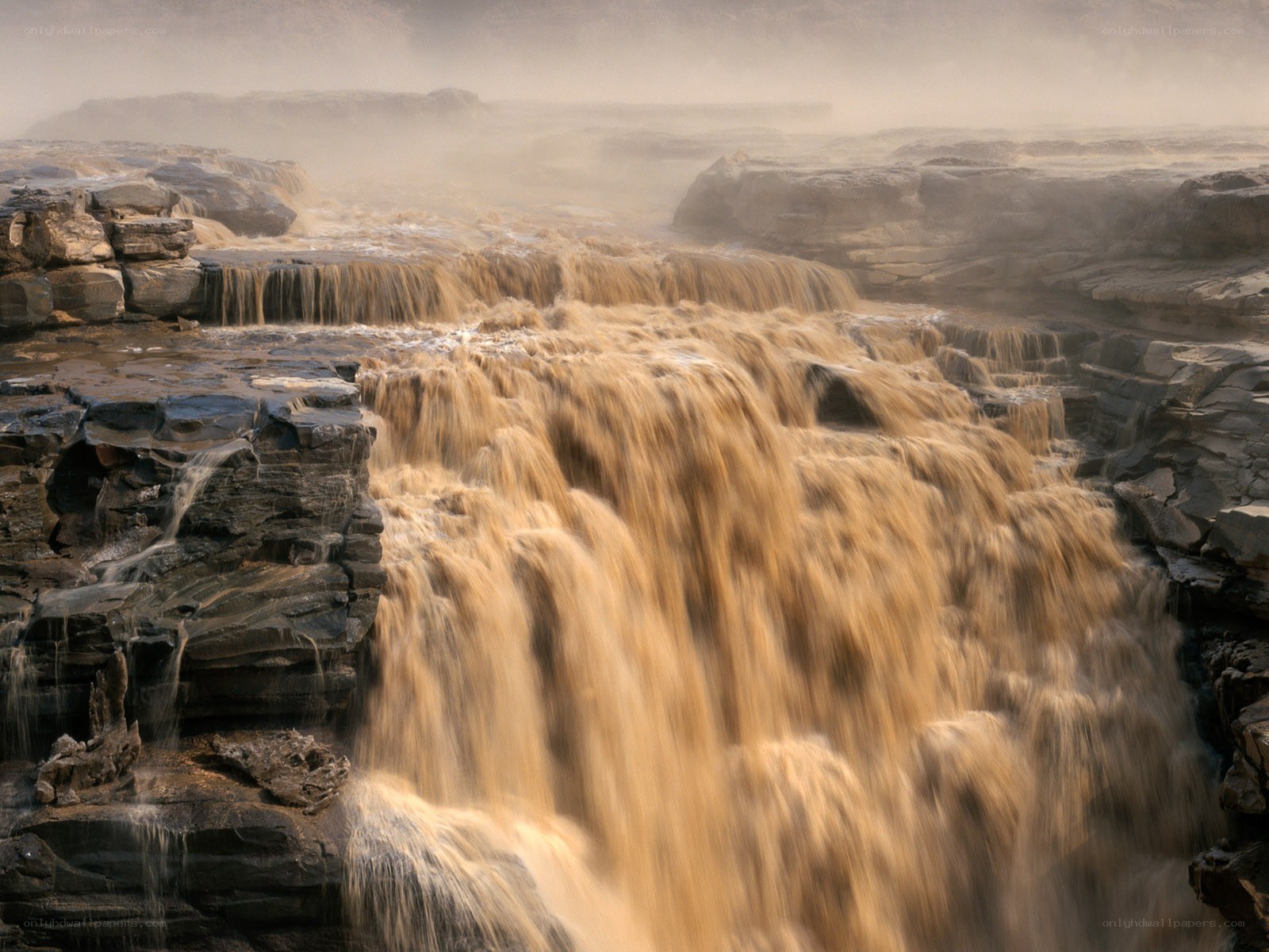 Muddy waterfall cascading over rocks