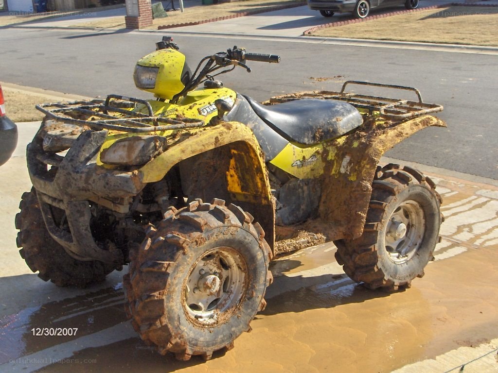 Muddy yellow ATV on driveway