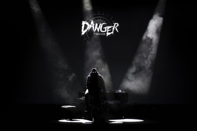 Musician on stage with 'DANGER' sign