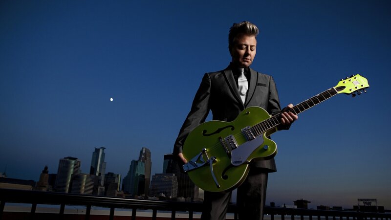 Musician with green guitar at dusk