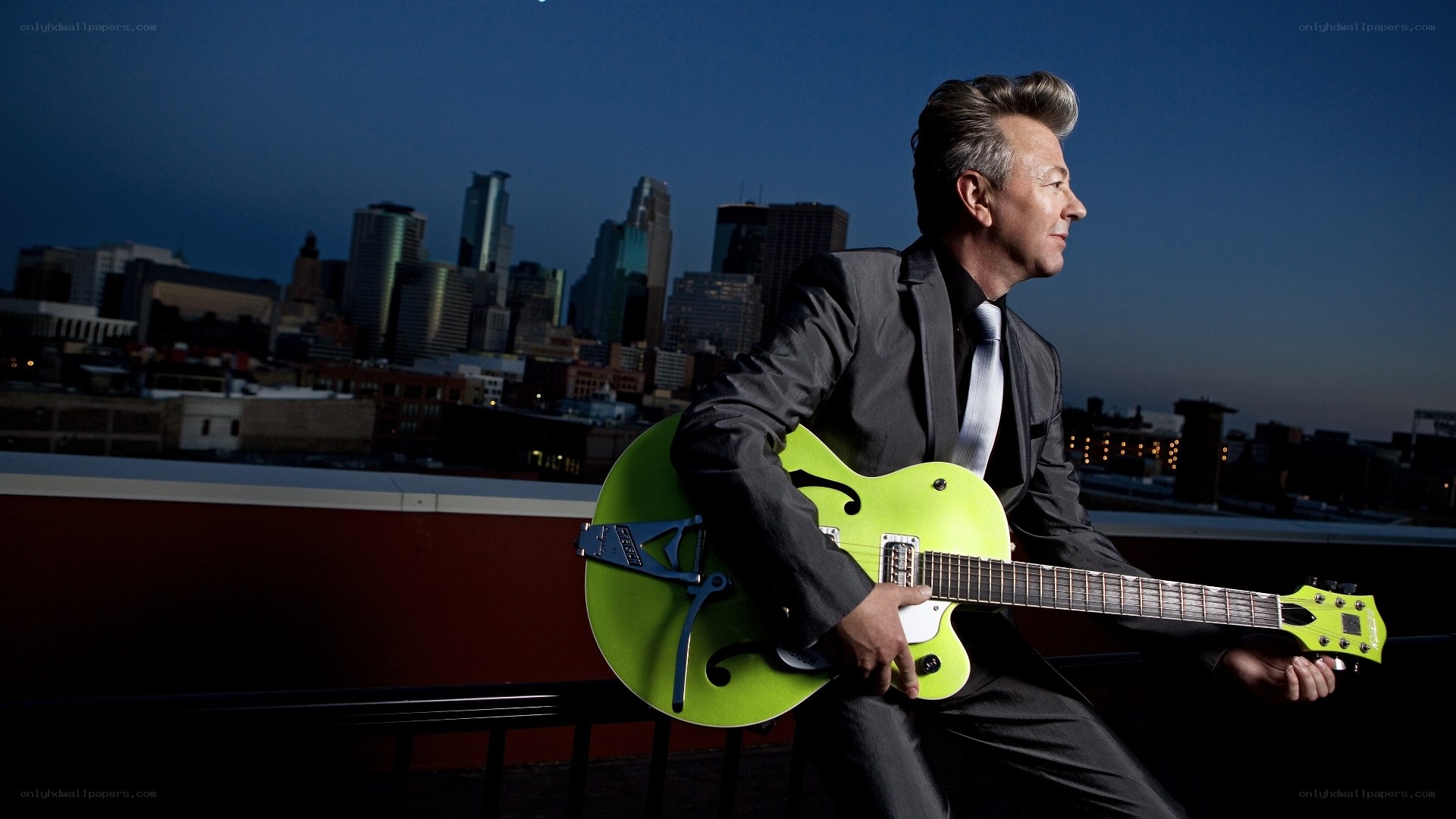 Musician with green guitar on rooftop