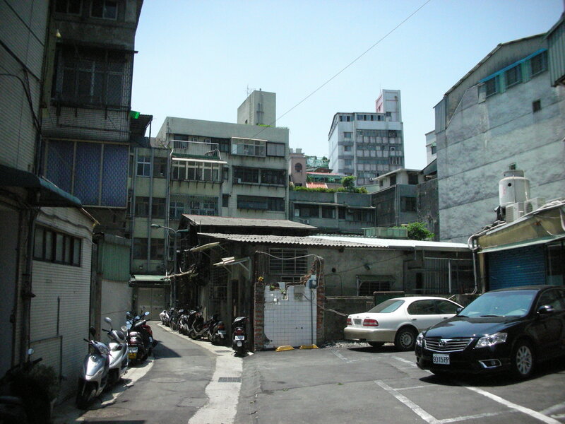 Narrow alley with parked cars and scooters