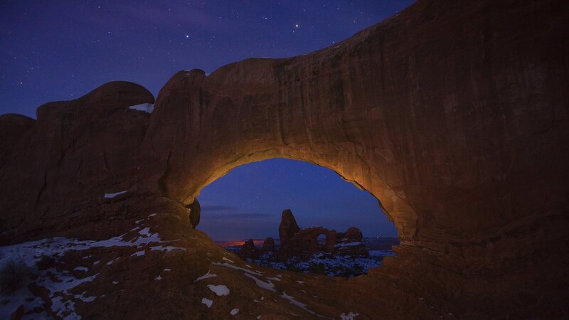 Natural rock arch under starry sky