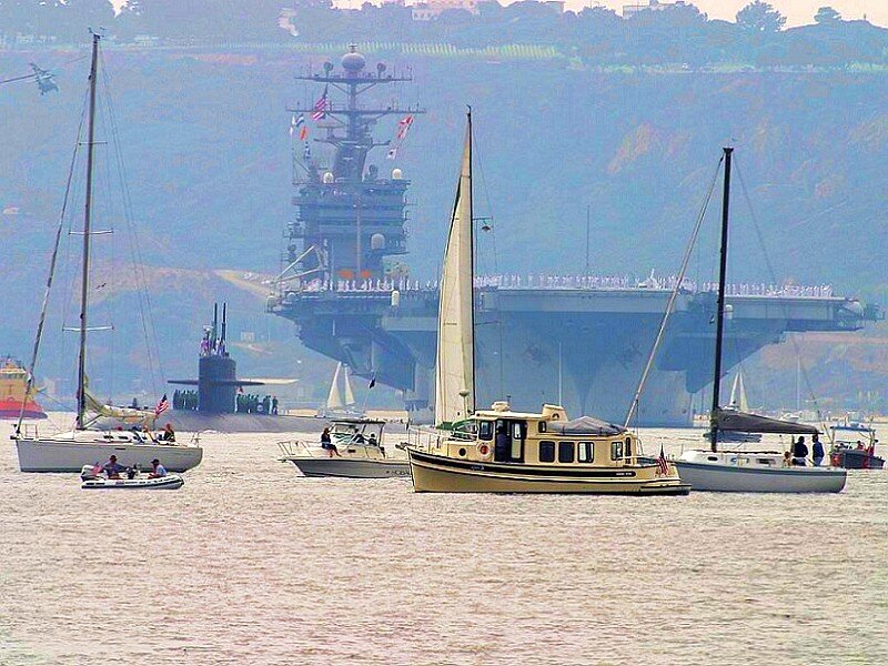 Naval ships and sailboats in harbor