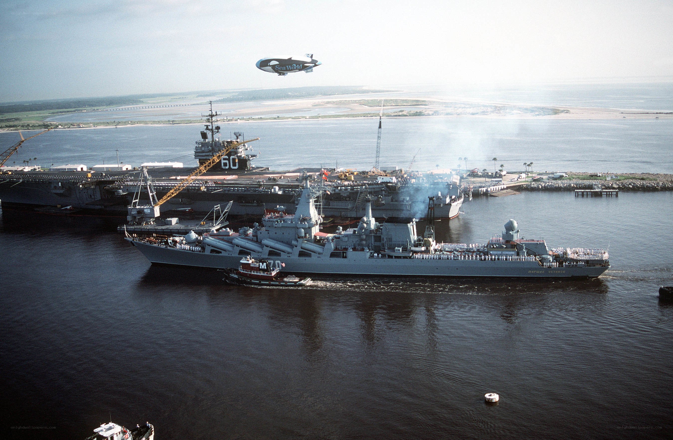 Naval ships in harbor with blimp