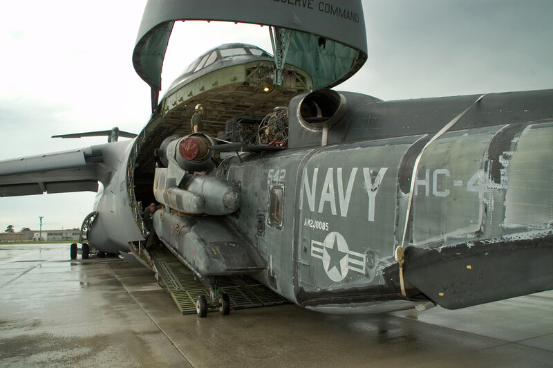 Navy helicopter being loaded into transport aircraft