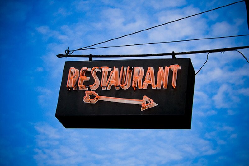 neon restaurant sign against blue sky