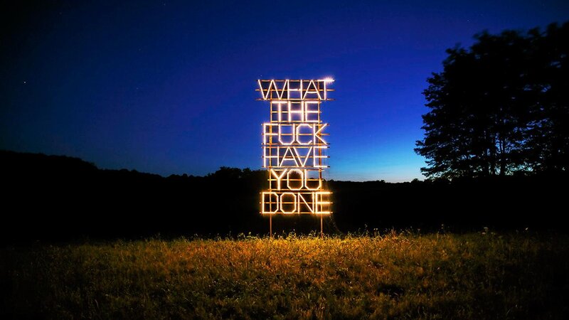 Neon sign in a field at night