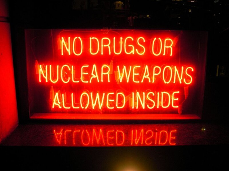 Neon sign warning about drugs and weapons
