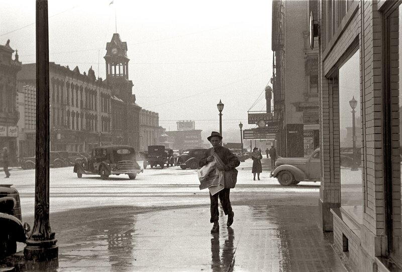 Newspaper boy on a wet city street