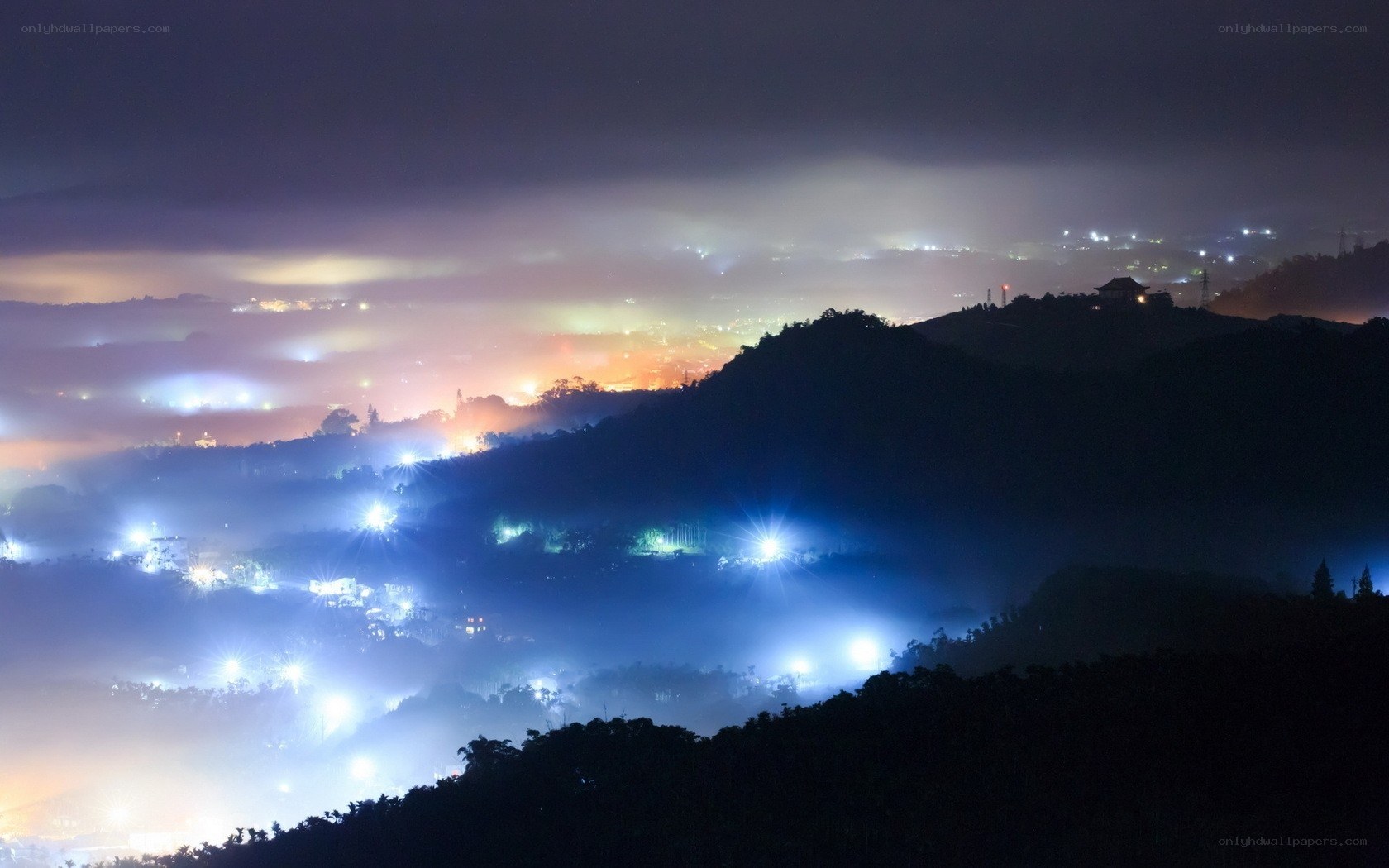 Night lights over misty hills