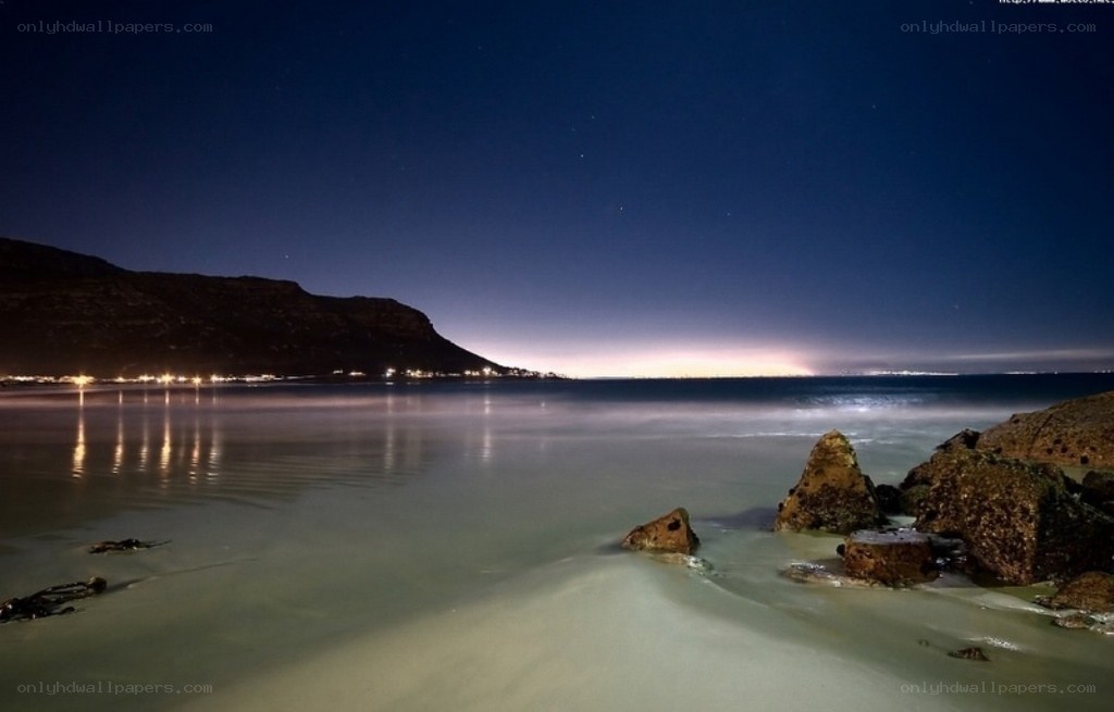 Nighttime beach with city lights