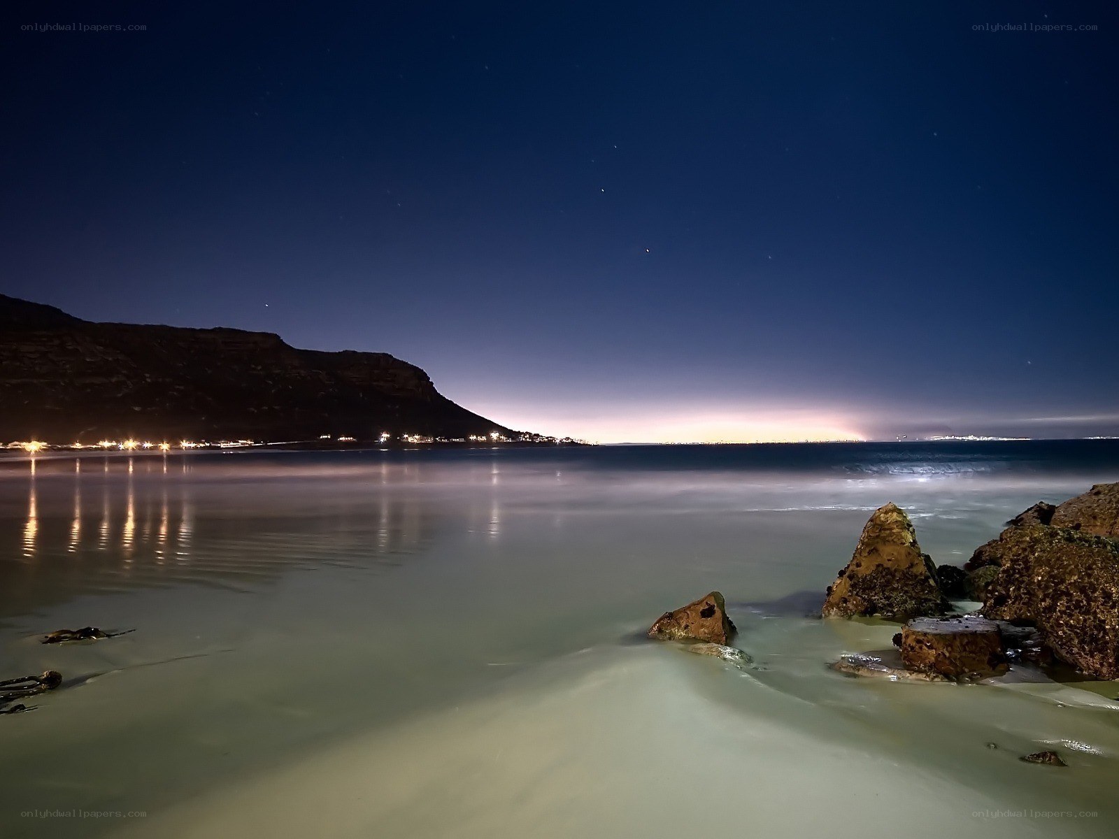 nighttime beach with city lights
