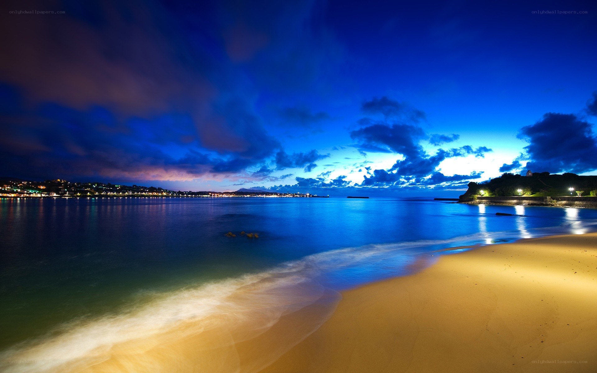 nighttime beach with city lights