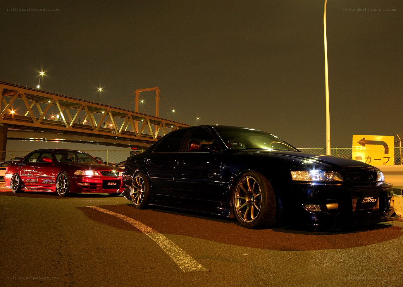 Nighttime car meet under a bridge