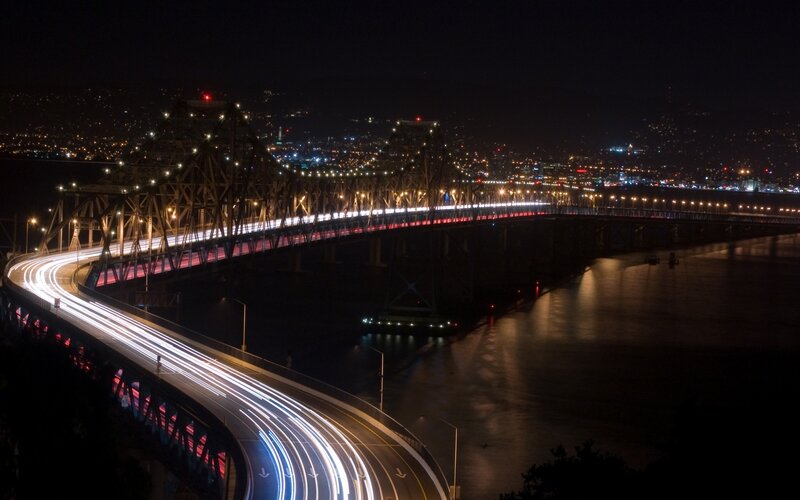 Nighttime city bridge with light trails