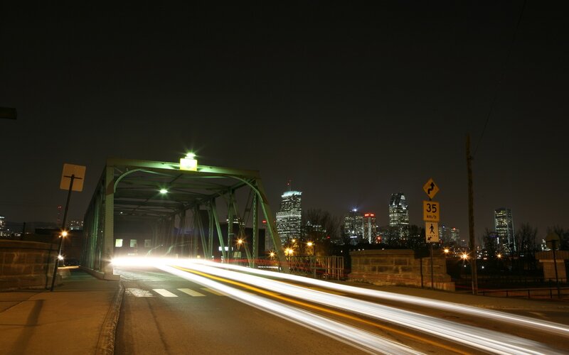 Nighttime city bridge with light trails