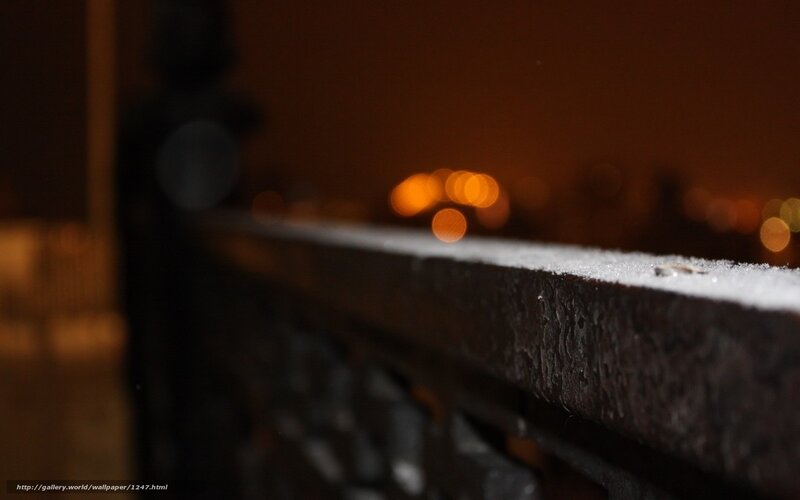 Nighttime city lights on a snowy railing