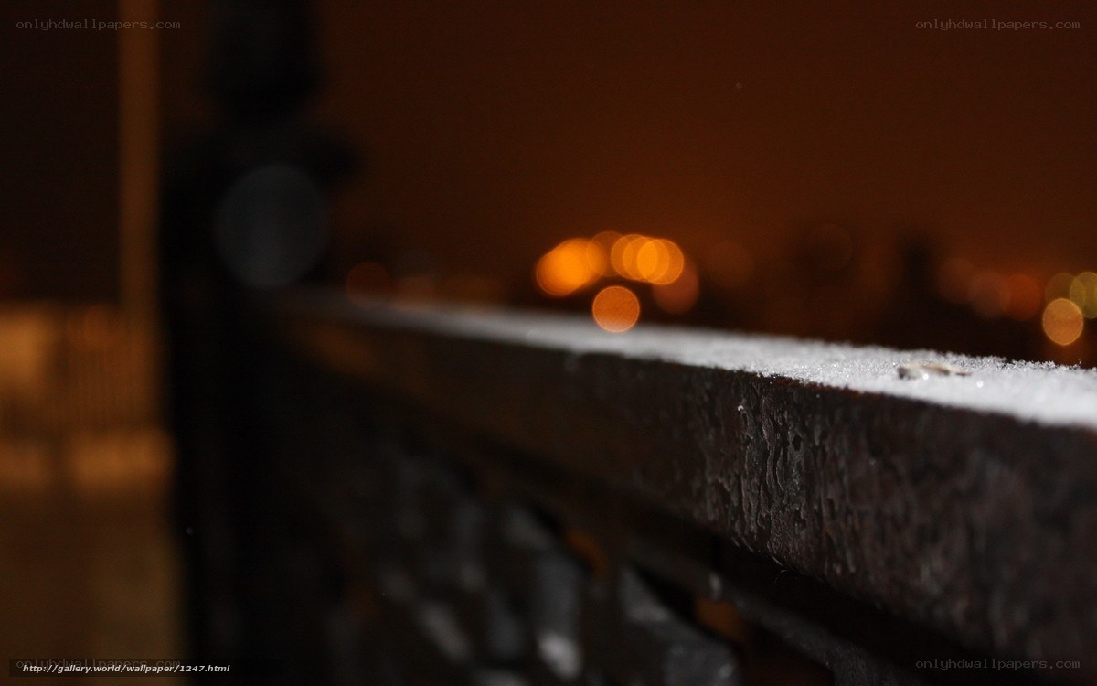 Nighttime city lights on a snowy railing